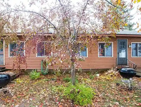 A red-brown Pioneer cottage among autumn trees