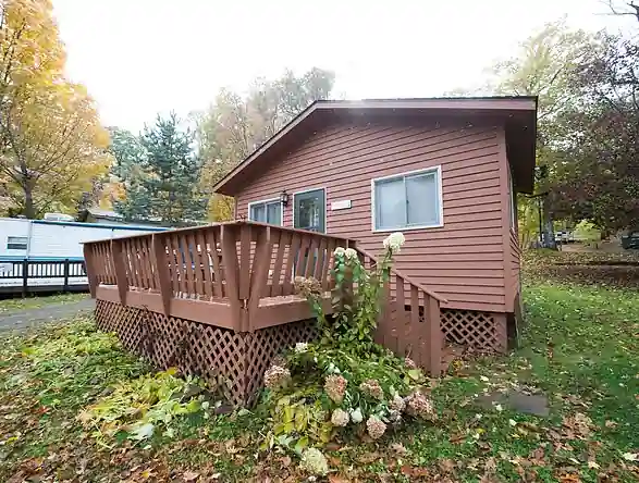 A red-brown Pioneer cottage with a deck among autumn trees