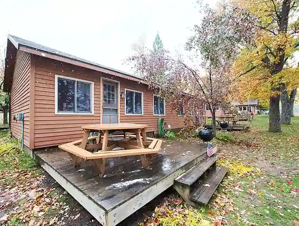 Pioneer cottage with a deck and US flag in the autumn woods