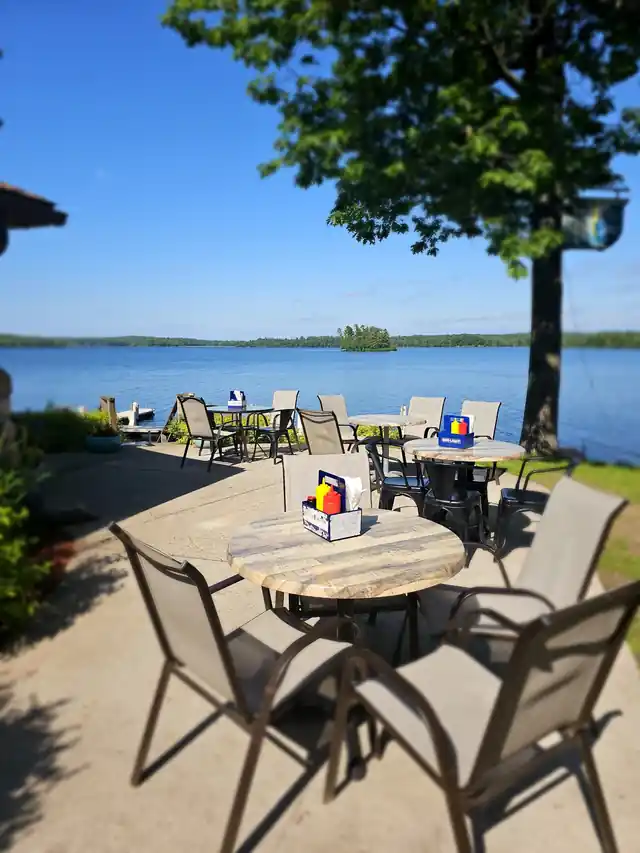 Patio tables on a clear day with blue Long Lake and an island behind