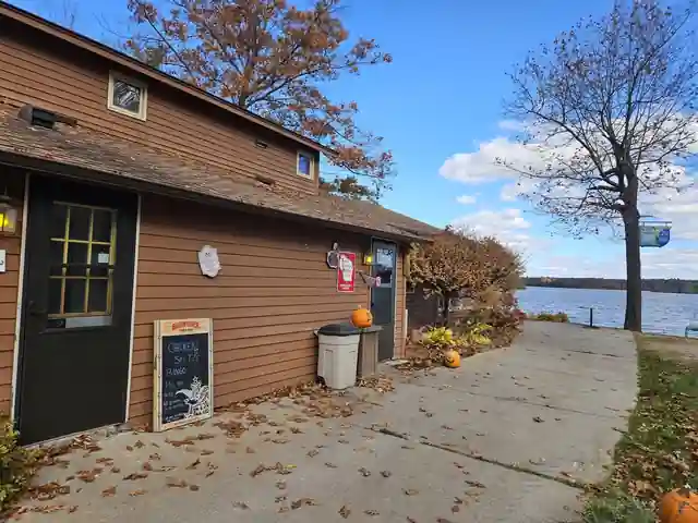 The brown lakeside Pioneer building with a chalkboard sign and the walkway down to the lake