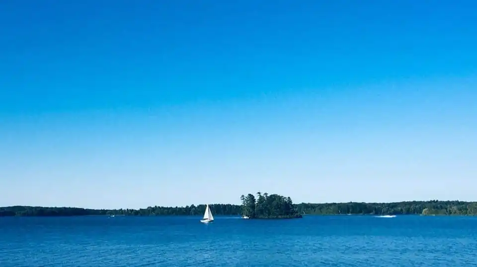 Open water on Long Lake with a sailboat and a wooded island