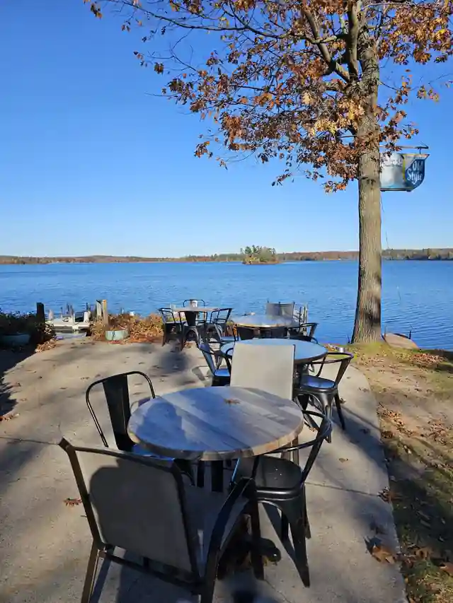 Lakeside patio tables under an autumn tree with Long Lake behind