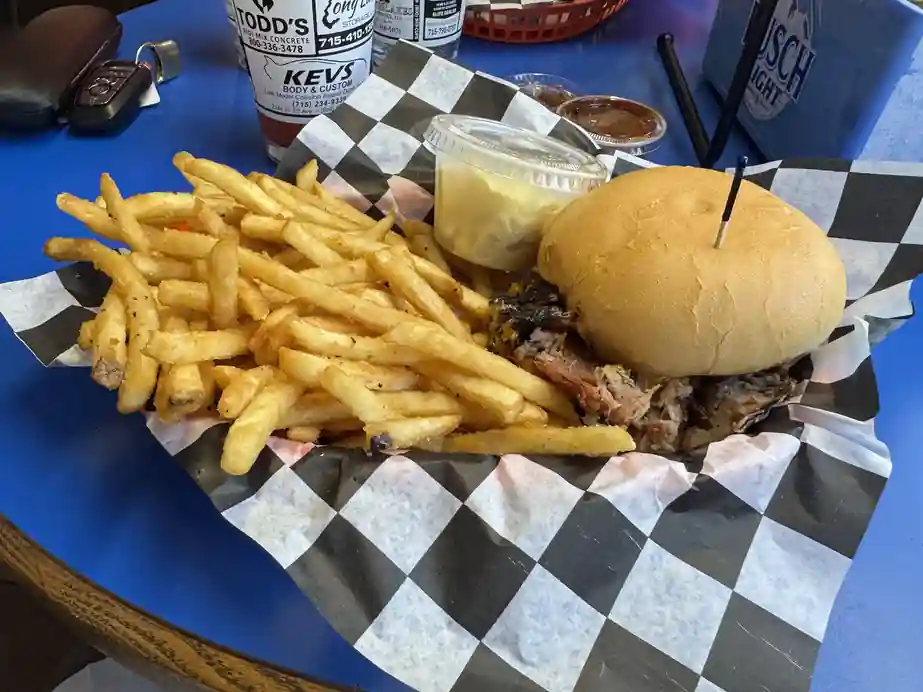 A smoked sandwich and seasoned fries in a basket at the Pioneer