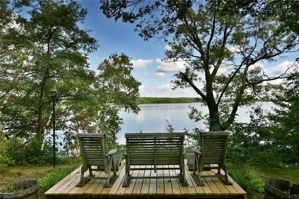 Three Adirondack-style benches on a deck over Long Lake at the Island Cabin