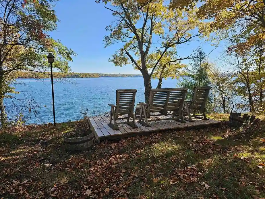 Rocking chairs on a small deck above blue water on the Island Cabin in autumn