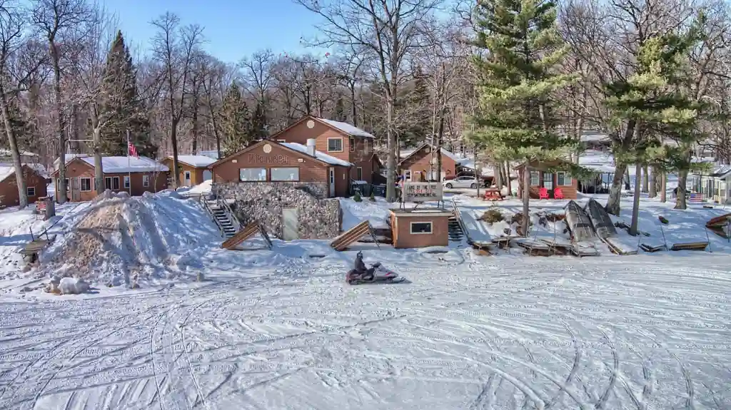 Snow-covered Pioneer cabins with a snowmobile rider on the trail
